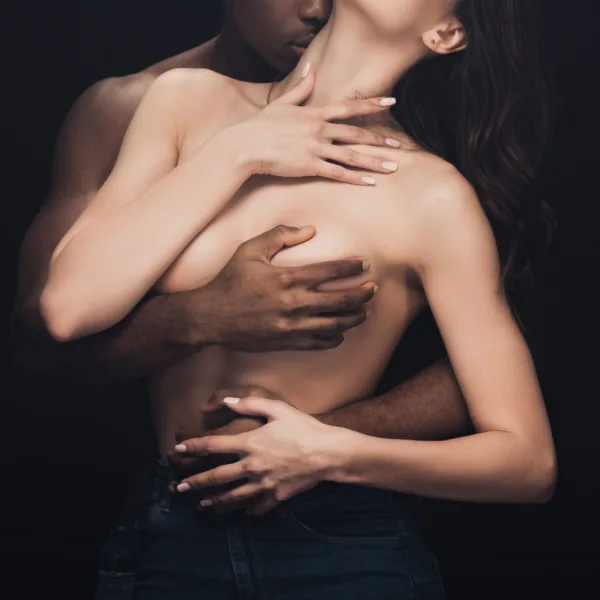 Uomo che accarezza il seno e la pancia di una donna, stimolando zone erogene femminili con abbraccio sensuale.